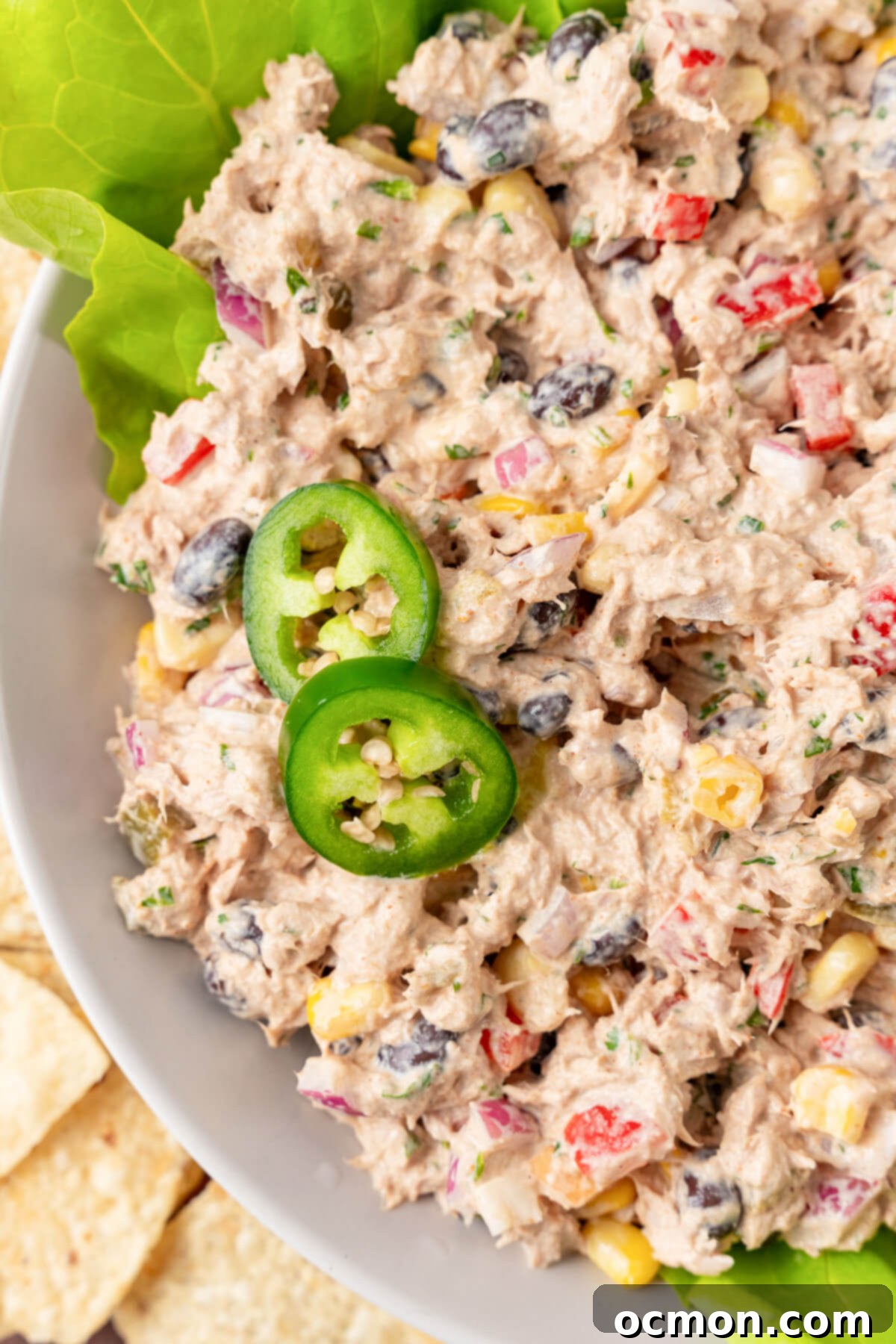 Close-up of the Mexican Tuna Salad in a bowl, showing the vibrant colors of corn, red bell pepper, and cilantro, topped with fresh jalapeño slices.