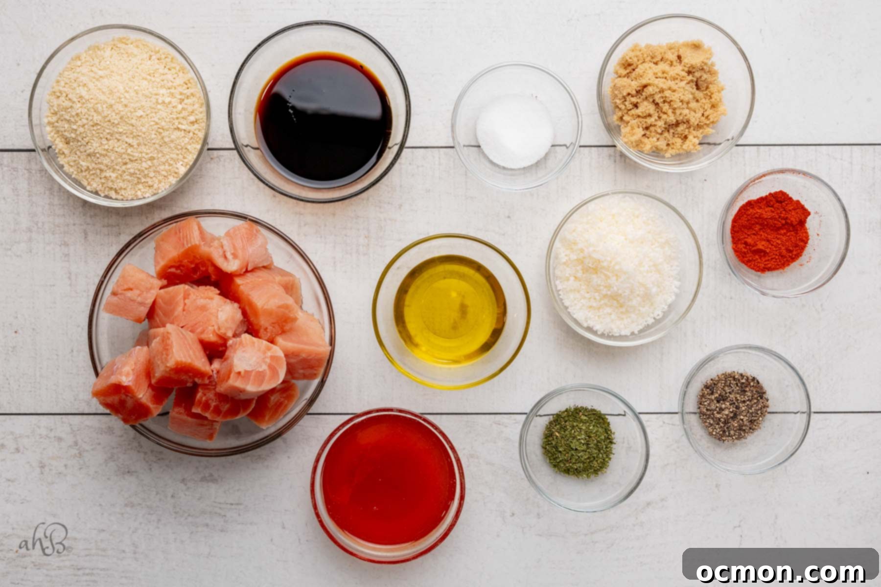 All the fresh and dry ingredients meticulously separated into clear glass bowls on a clean kitchen counter, ready to be assembled for the hot honey salmon bites recipe.