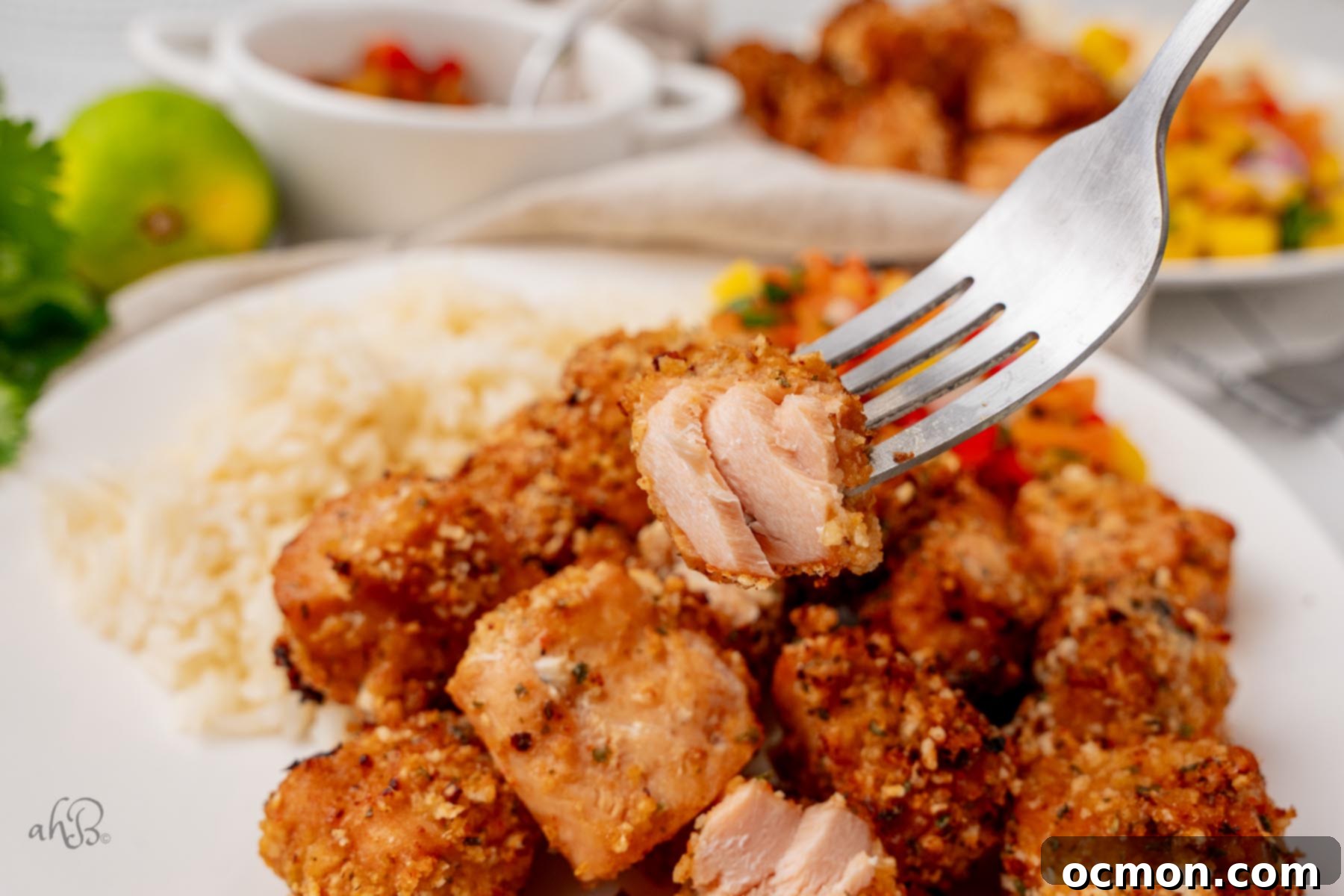 Close-up of crispy and tender Air Fryer Hot Honey Salmon Bites, garnished with fresh herbs, ready to be served.
