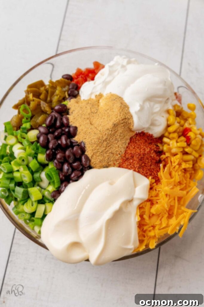 Step 1: All prepared ingredients for the Fiesta corn dip are combined in a large mixing bowl, ready to be mixed. 