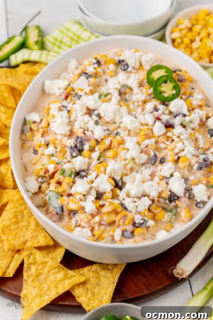 Step 3: A serving bowl of prepared Fiesta corn dip is being topped with crumbled queso fresca cheese just before serving. 