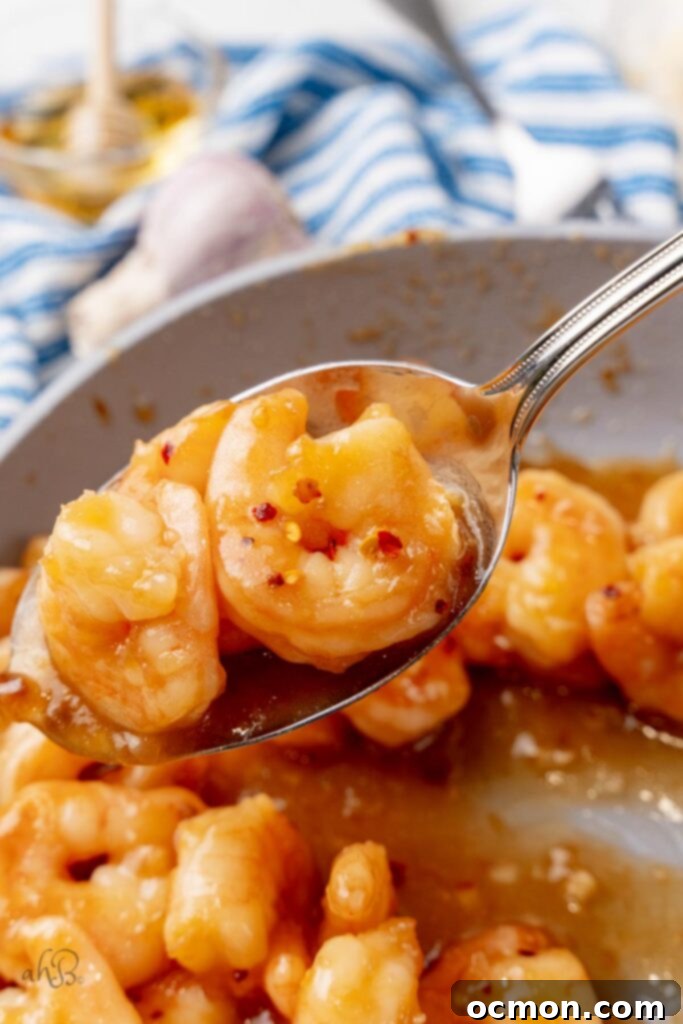 A close up image of 3 honey garlic shrimp in a serving spoon. 