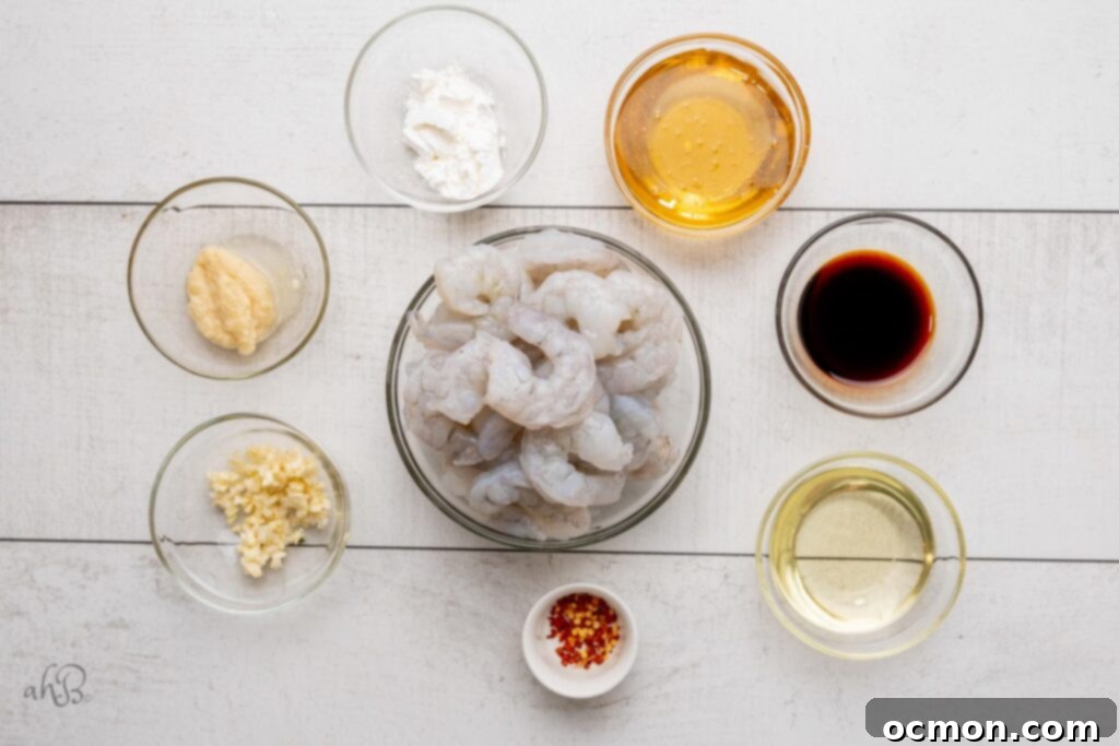 The ingredients needed to make honey garlic shrimp: chopped garlic, minced ginger, cornstarch, honey, soy sauce, vegetable oil, crushed red pepper, and raw shrimp.