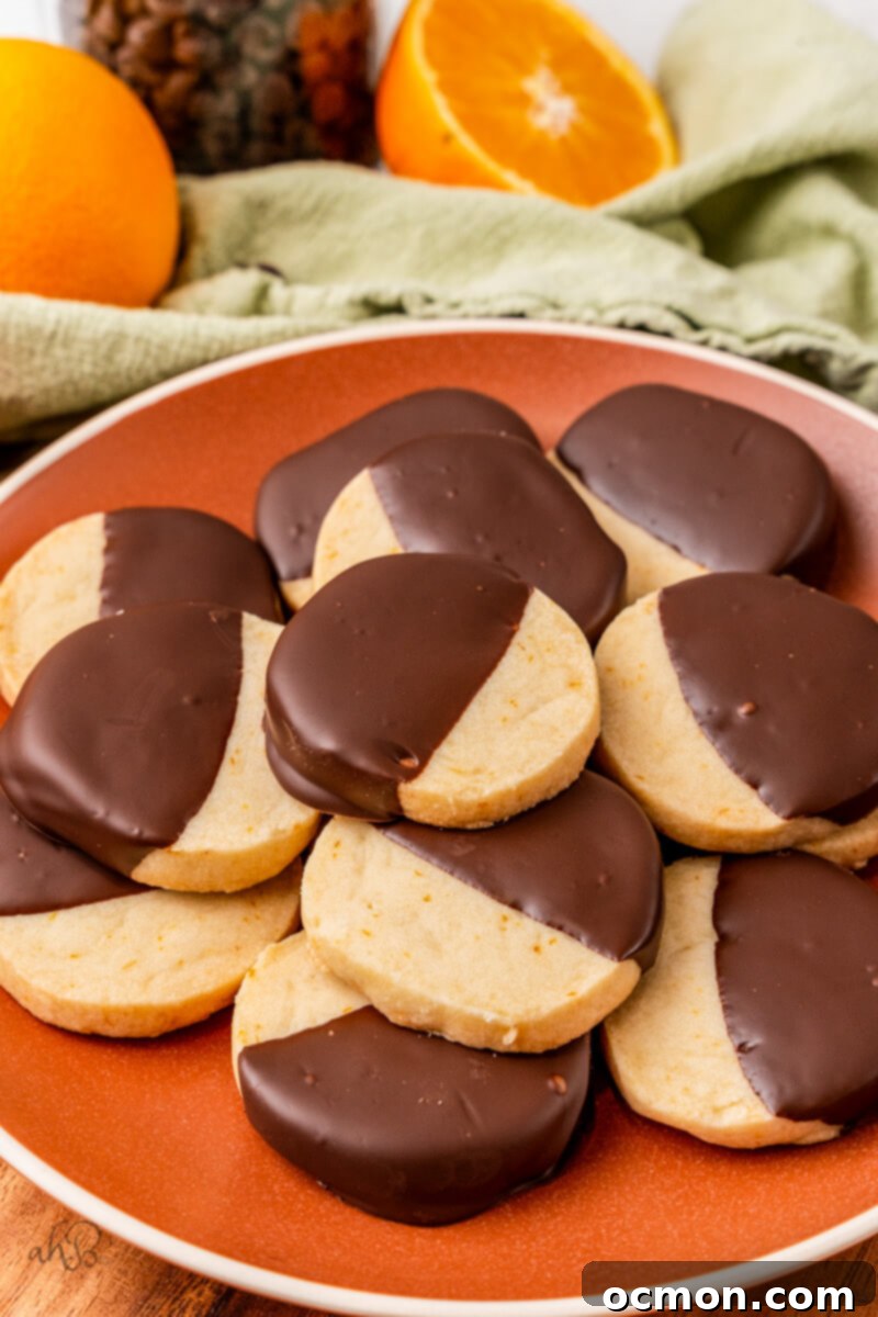 Orange Zest Chocolate Shortbread 3 A vibrant red plate full of meticulously crafted dark chocolate dipped orange shortbread cookies, ready to be enjoyed as festive treats.