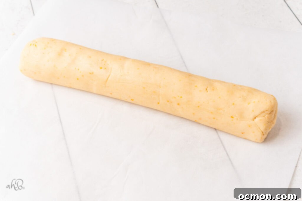 Orange Zest Chocolate Shortbread 9 Shortbread dough meticulously shaped into a log and wrapped in parchment paper, prepared for chilling to achieve perfect sliceable cookies.