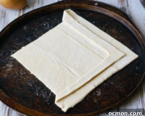 Sliced pears and plums arranged on puff pastry dough