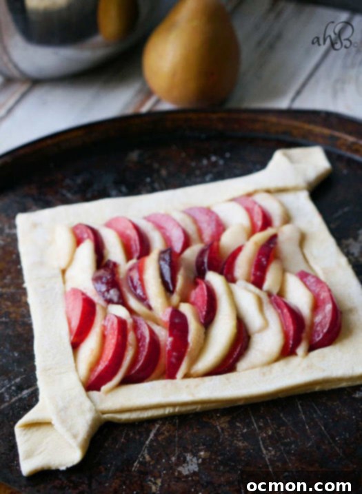 Ready-to-bake pear and plum galette on a baking sheet