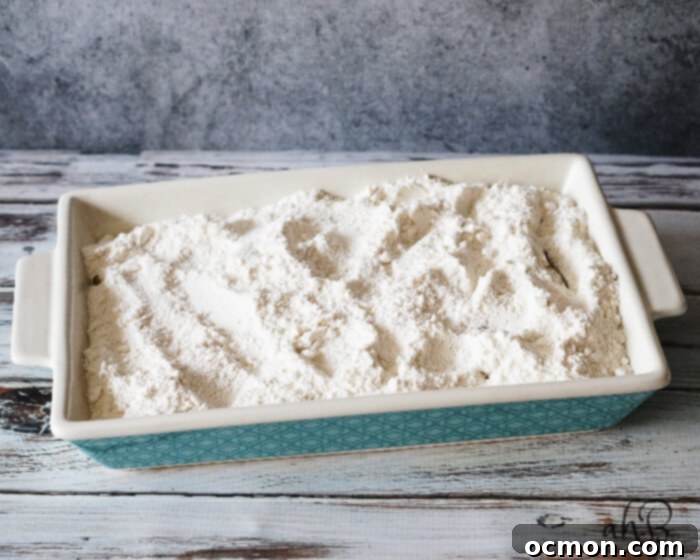 A dry package of yellow cake mix forms the third layer of the dump cake, spread evenly over the caramel and apples.