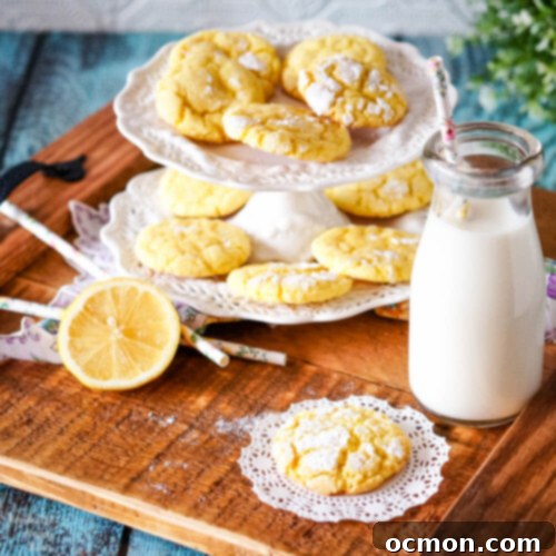 A wooden tray holding a plate of bright yellow lemon crinkle cookies, a glass milk bottle, and a sliced lemon, emphasizing their fresh, homemade appeal.
