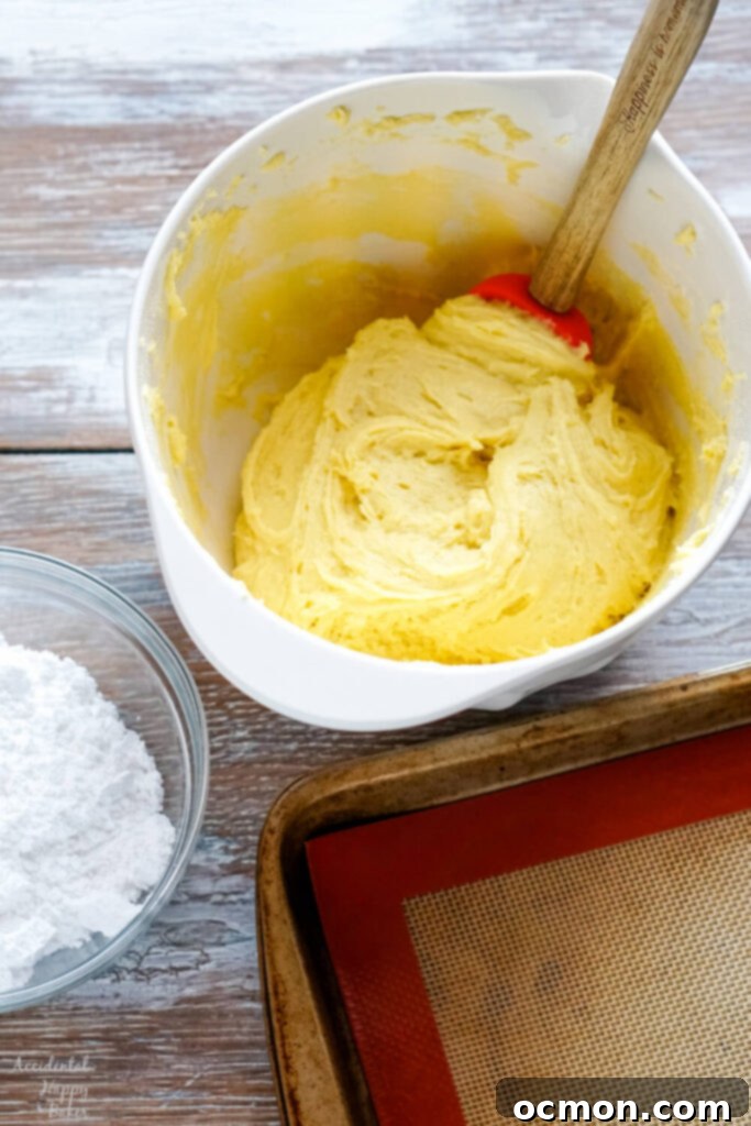 Step one of making lemon crinkle cookies: combining the lemon cake mix with softened butter and eggs in a mixing bowl until a dough forms.