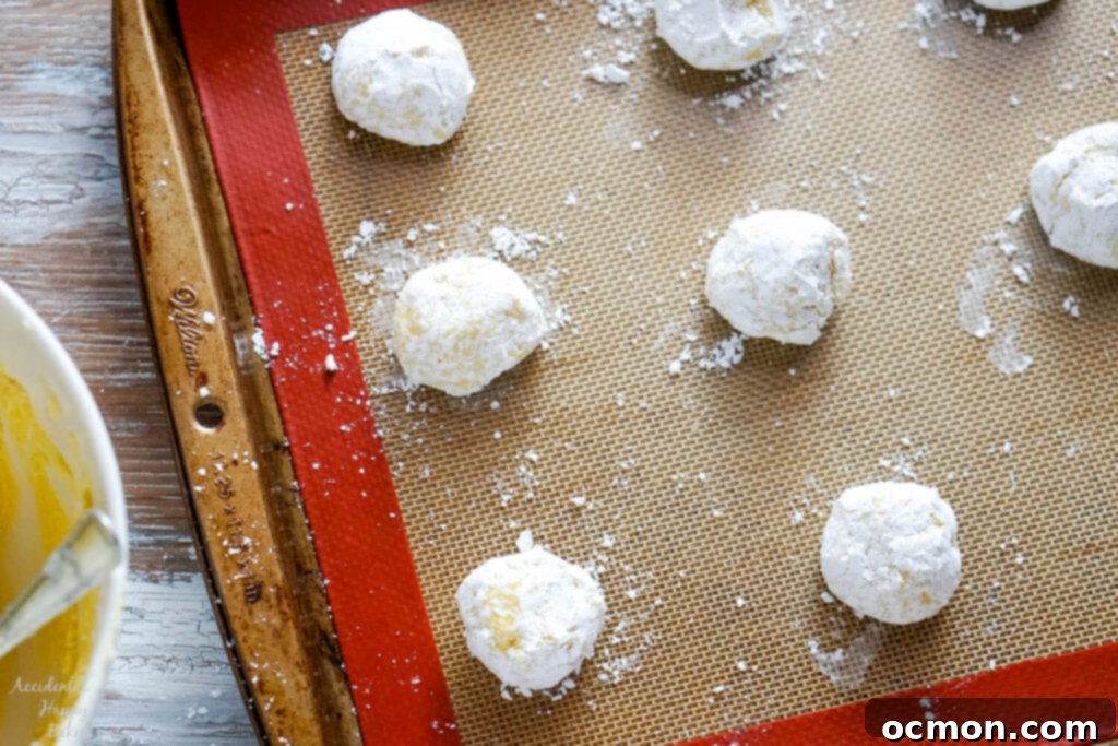 Step three: placing the powdered sugar-coated lemon crinkle cookie dough balls two inches apart on a baking sheet, ready to be baked to golden perfection.