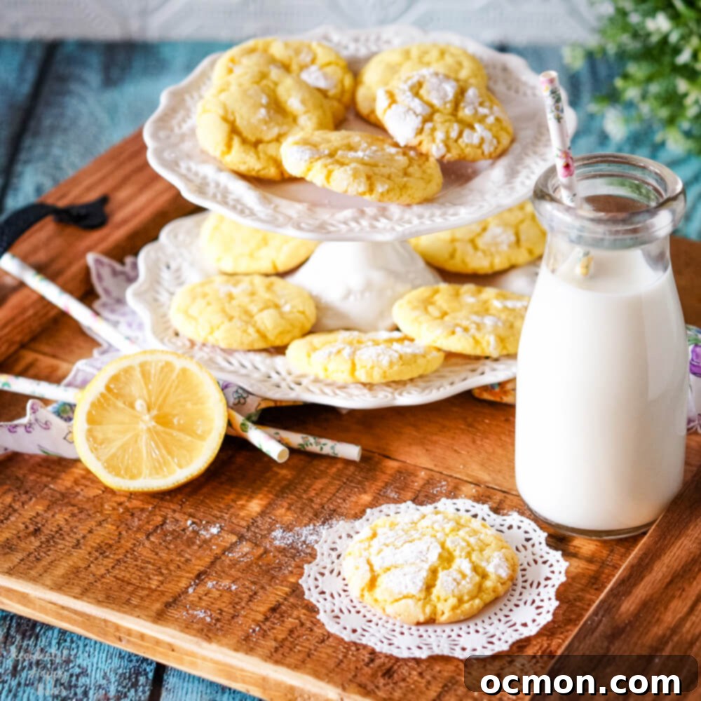 A close-up of a plate piled high with fluffy, powdered sugar-dusted lemon crinkle cookies, ready to be enjoyed.