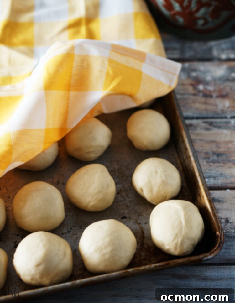 Hawaiian rolls rising on a baking sheet