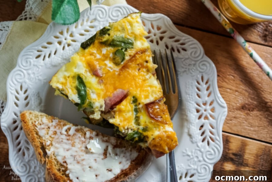 Hearty Ham, Asparagus, and Potato Frittata 5 Ham, Asparagus, and Potato Frittata on a plate next to buttered toast and juice.