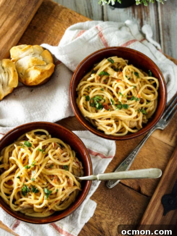 Spread of Crockpot Chicken Spaghetti alongside a salad and garlic bread rolls