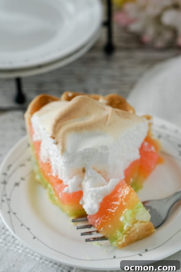 Pastel Peaks of Lemon Sunshine 4 A bite of rainbow lemon meringue pie rests on a fork, showing the layers of colored filling.