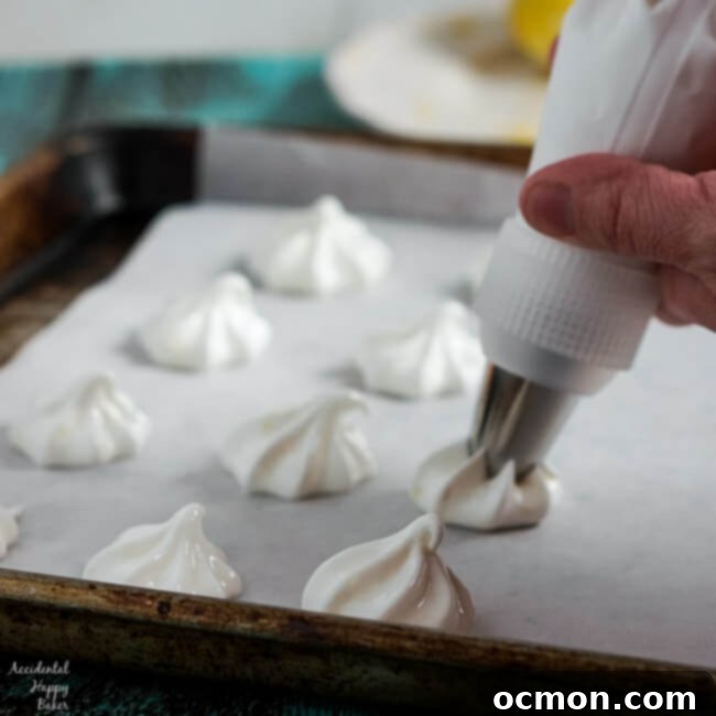 Piping star-shaped lemon meringues onto a baking sheet lined with parchment paper, showcasing the delicate process.
