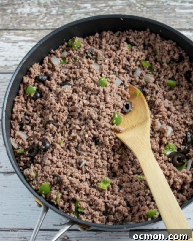 Ground beef and Italian sausage are cooked with diced onion, bell pepper, and minced garlic in a large skillet.