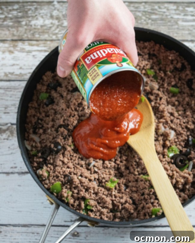 Rich pizza sauce is stirred into the browned ground beef and Italian sausage mixture with vegetables.