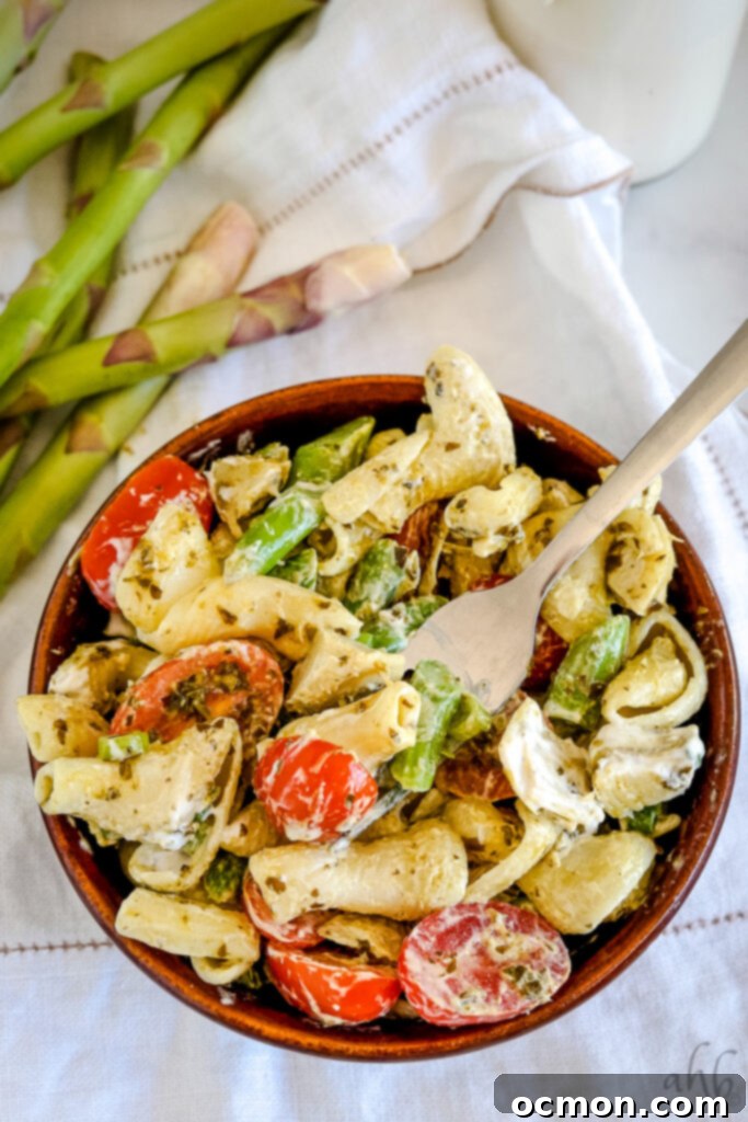 A large serving bowl filled with creamy pesto pasta salad, ready for a gathering.
