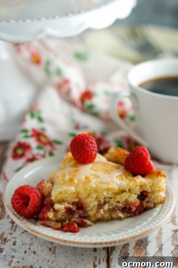 A slice of raspberry coffee cake sitting next to a cup of coffee.