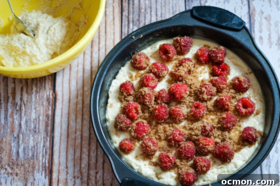 Raspberries and brown sugar are sprinkled over the cake batter. 