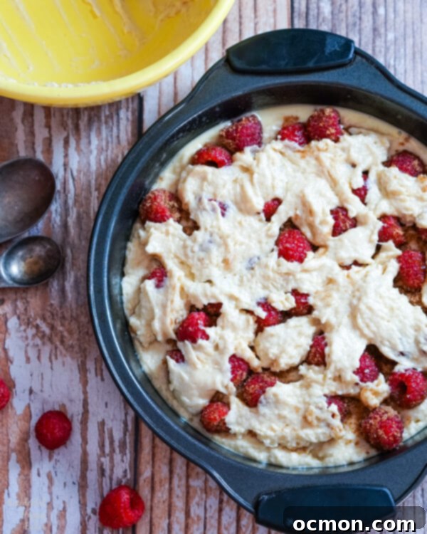 Spoonfuls of cake batter are dropped evenly over the top of the raspberry layer. 