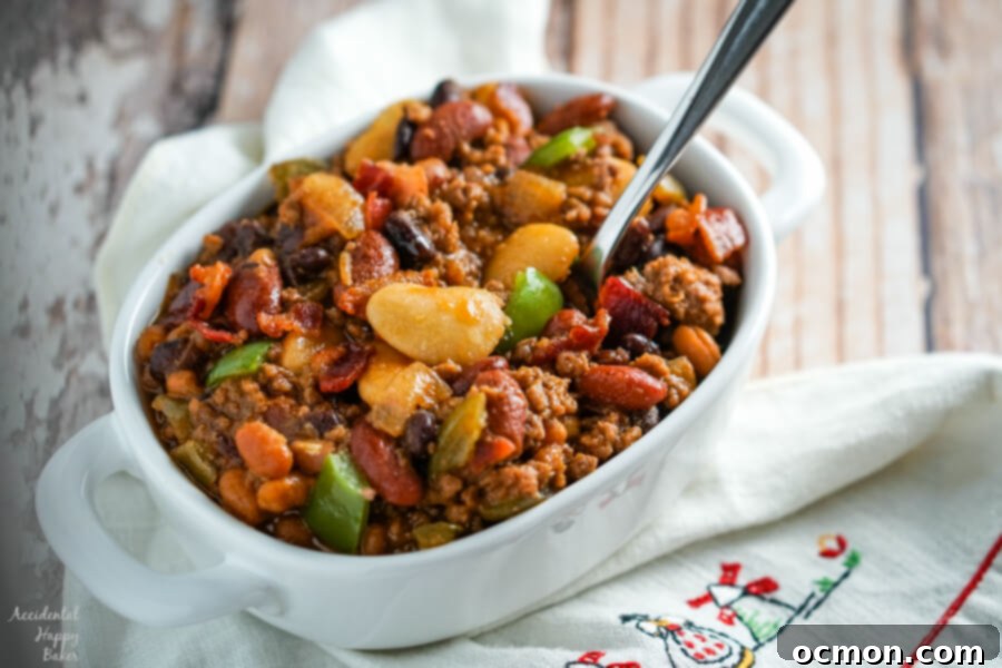 Slow Cooker Calico Beans in a bowl, showing the variety of colorful beans, ground beef, and bacon in a rich, sweet and tangy sauce, ready to be served.