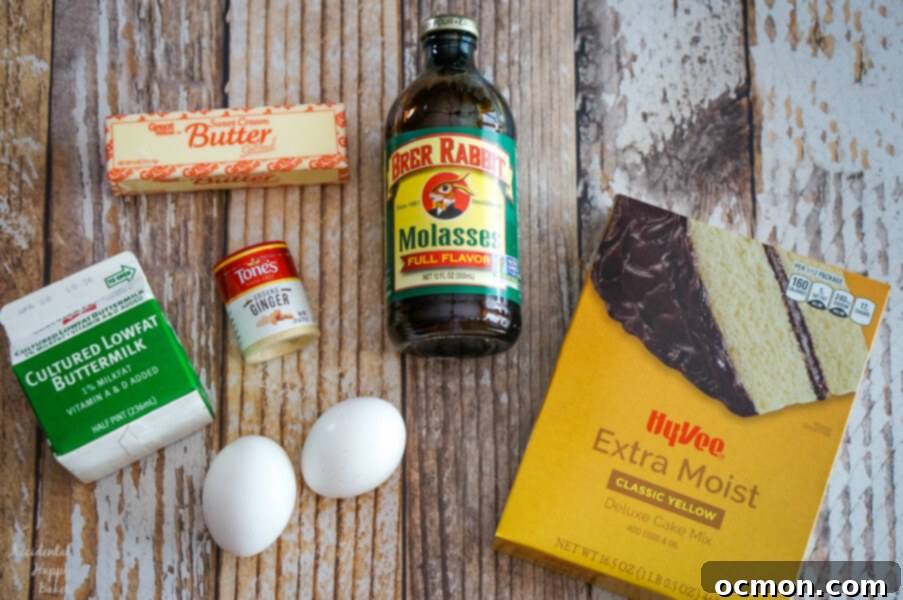 Deep Molasses Skillet Cake 3 A collection of Molasses Skillet Cake ingredients laid out on a rustic wooden surface, including a box of yellow cake mix, fresh eggs, ground ginger, a jug of buttermilk, melted butter, and a bottle of rich molasses.