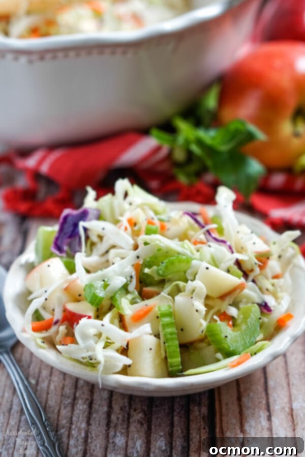 Shredded cabbage, celery, and apples mixed with homemade poppyseed dressing in a small bowl. 