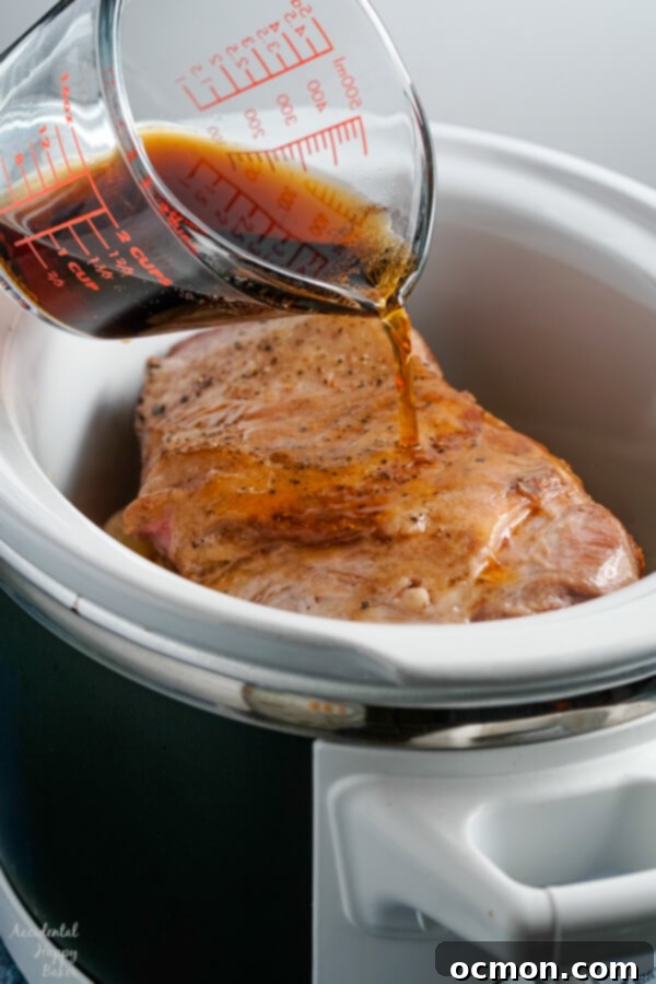 Root beer is poured over the pork, apples and onions into the slow cooker.