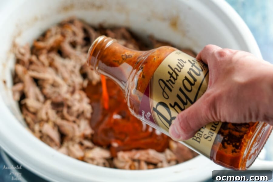 A bottle of barbecue sauce is added to the pulled pork. 