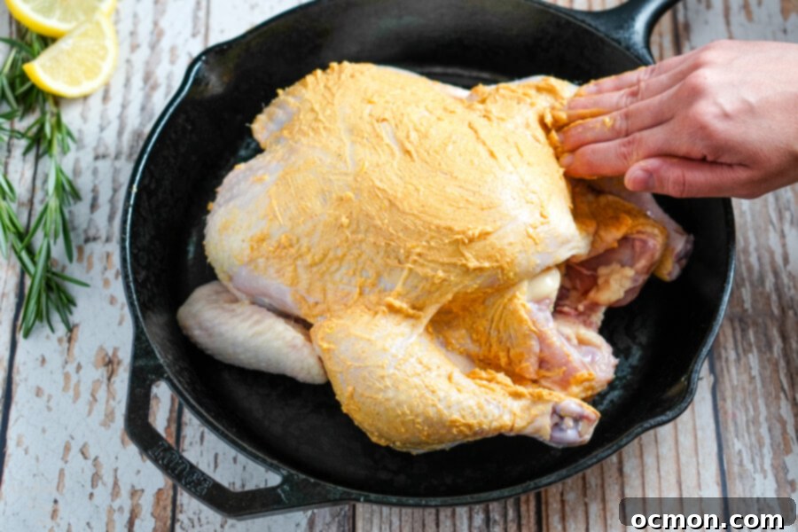 Golden Roast Chicken 7 Seasoned butter being rubbed under the chicken skin for enhanced flavor.