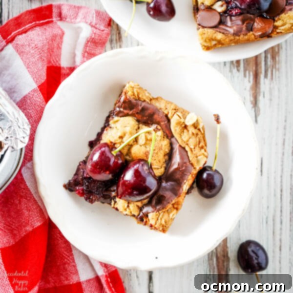 A close up of a cherry revel bar on a white plate surrounded by fresh cherries. 
