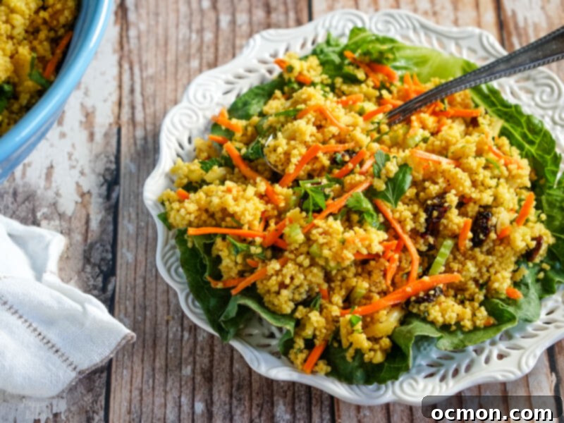Golden Curried Couscous Salad 6 A single serving of curried couscous salad artfully presented on a crisp lettuce leaf on a white serving plate.