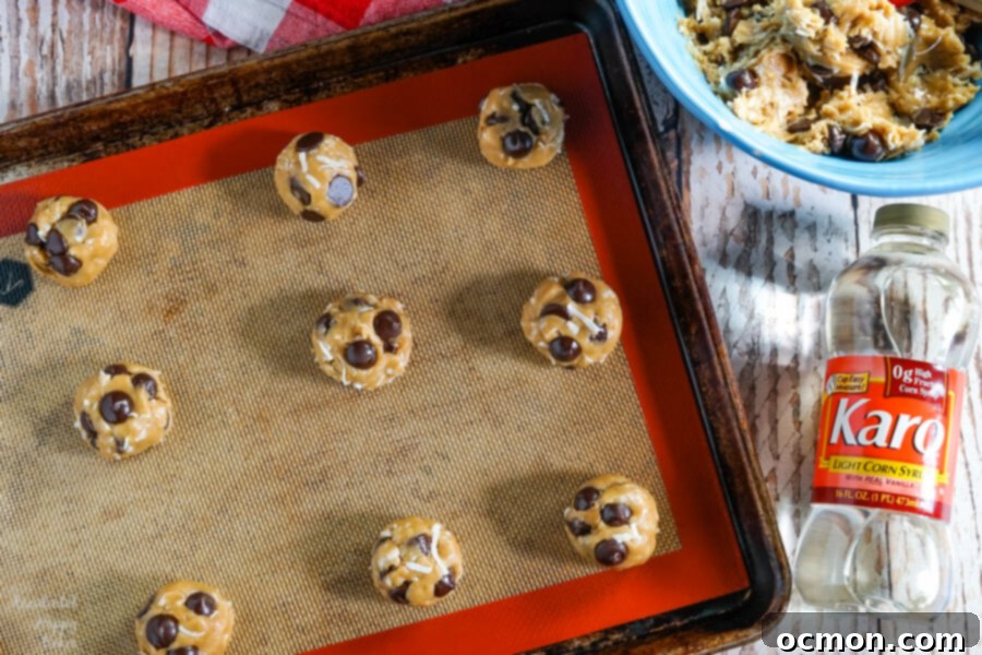 Balls of coconut chocolate chip cookie dough on a baking sheet ready to go into the oven.