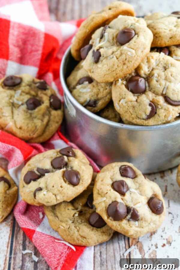 Chewy Coconut Chocolate Chip cookies stacked on a red checked towel and nestled in a metal bucket.
