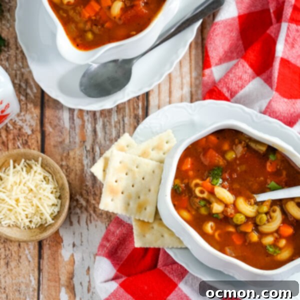 Hamburger macaroni soup, a hearty and budget-friendly dish, made in less than 30 minutes. Served in a white bowl with crackers on the side.