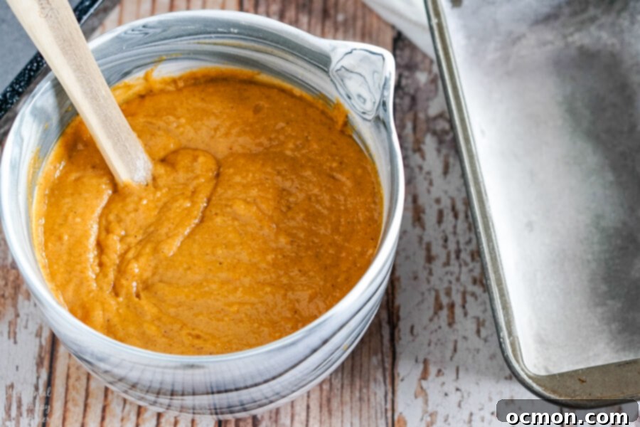 Close-up of Downeast Maine Pumpkin Bread batter being mixed in a bowl, showing its smooth texture.