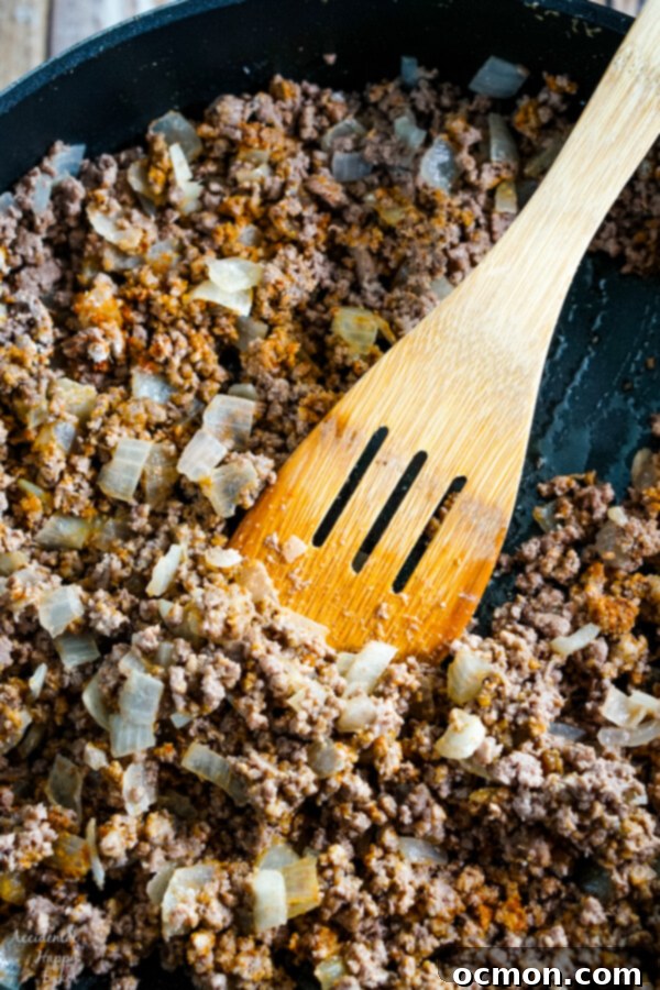 The seasonings are added to the ground beef in the pan. 
