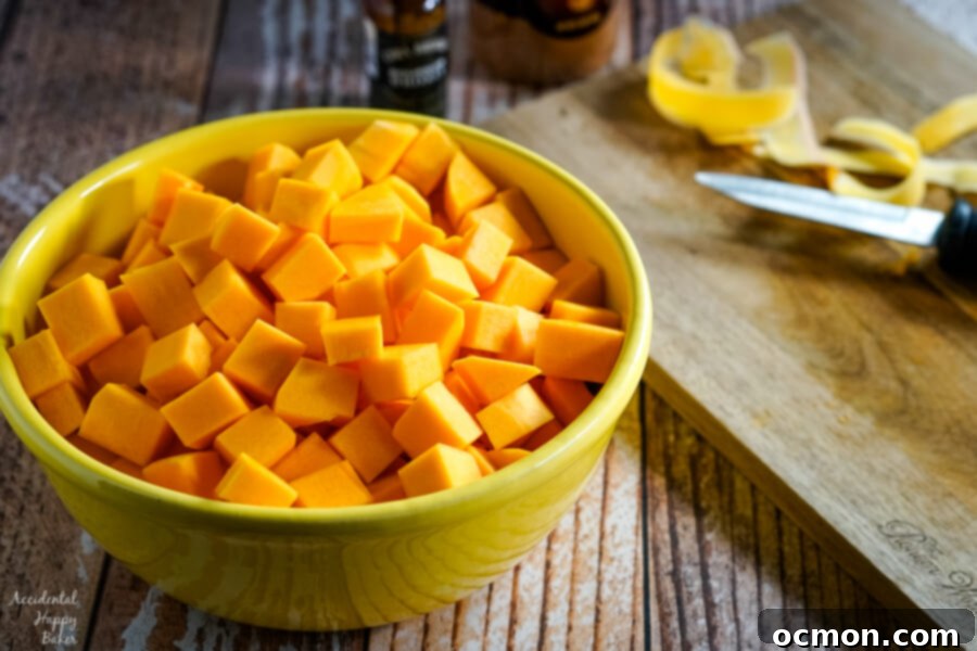 A vibrant yellow bowl brimming with peeled and chopped butternut squash, ready for seasoning, resting beside a cutting board and a sharp knife, indicating preparation is underway.