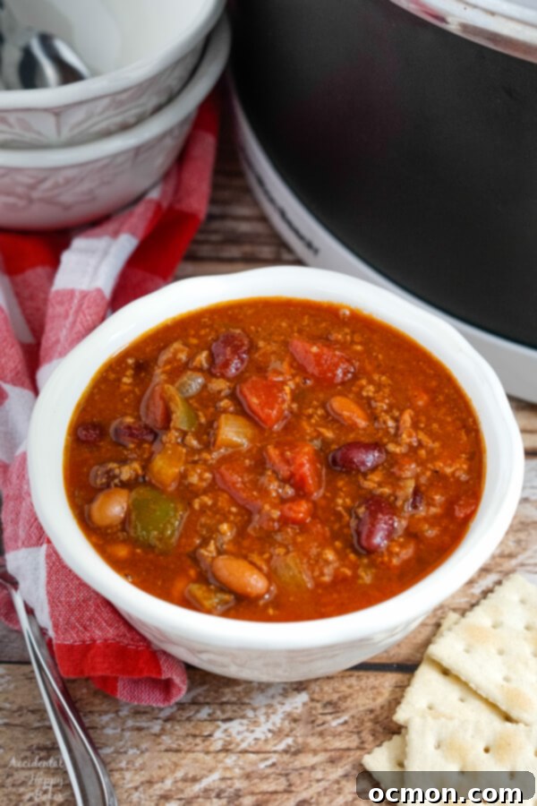 A white bowl of Wendy's copycat chili next to a slow cooker. 