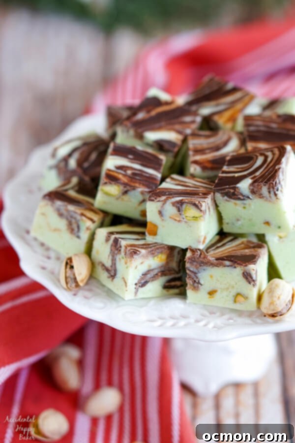 A white platter stacked high with Pistachio Swirl Fudge and pistachios. 