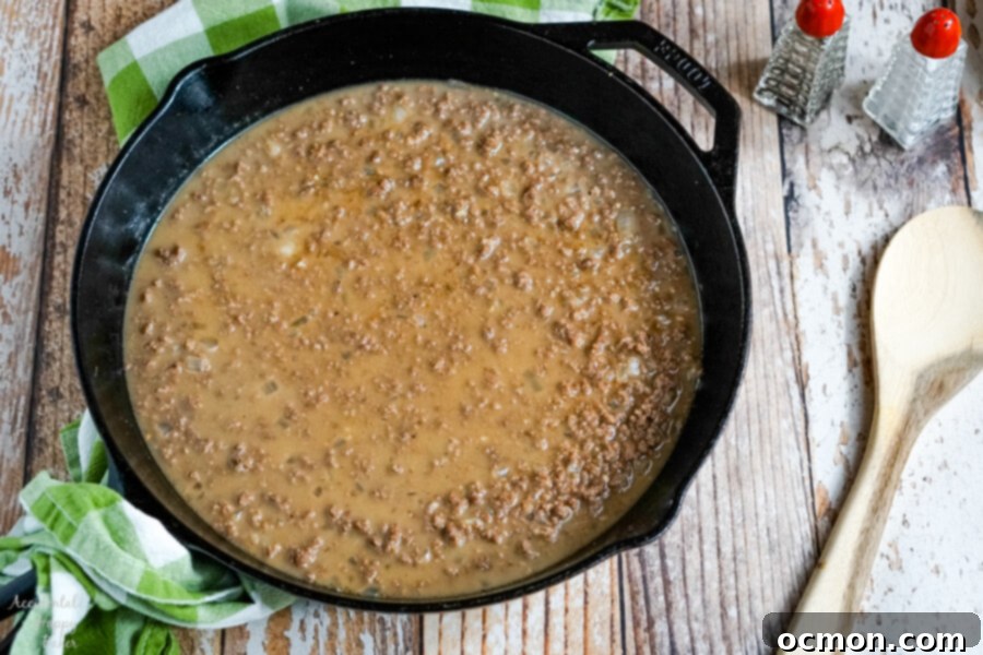 Crispy Tater Tot Shepherds Pie 4 Shepherd's Pie with Tater Tots starts with ground beef in a rich gravy sauce, simmering in a skillet.