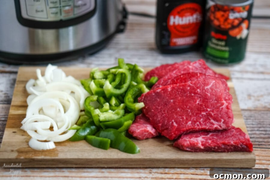 Onions, peppers, and steaks sitting in front of the Instant Pot with bbq sauce and tomatoes in the background. 