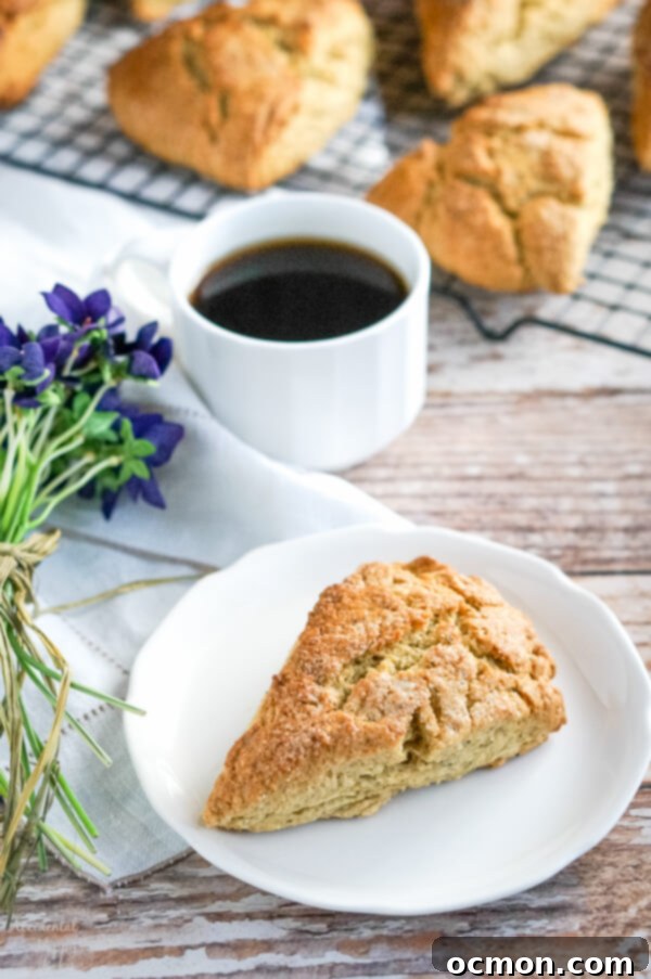 A scone on a white plate sitting in front of a cup of Earl Grey tea. 