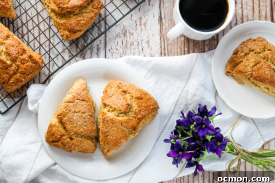 Two scones on a white plate next to a wire rack full of scones. 