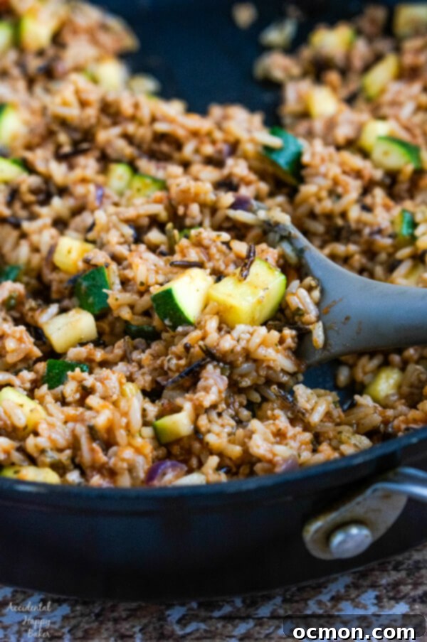 Sausage and onion browning in a skillet on the stovetop, forming the base of the flavorful wild rice stuffing.