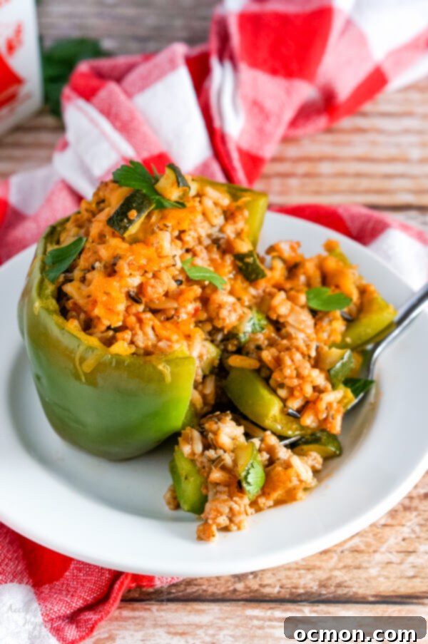 A vibrant wild rice stuffed pepper, sliced in half to show the rich, savory filling within, garnished with fresh herbs.