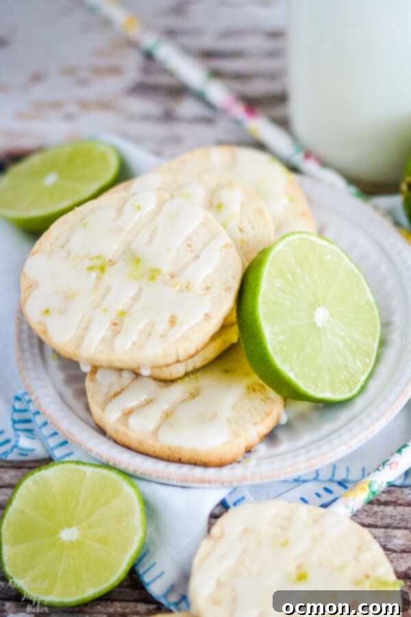 Key Lime Shortbread Cookies stacked on a white plate with slices of lime. 